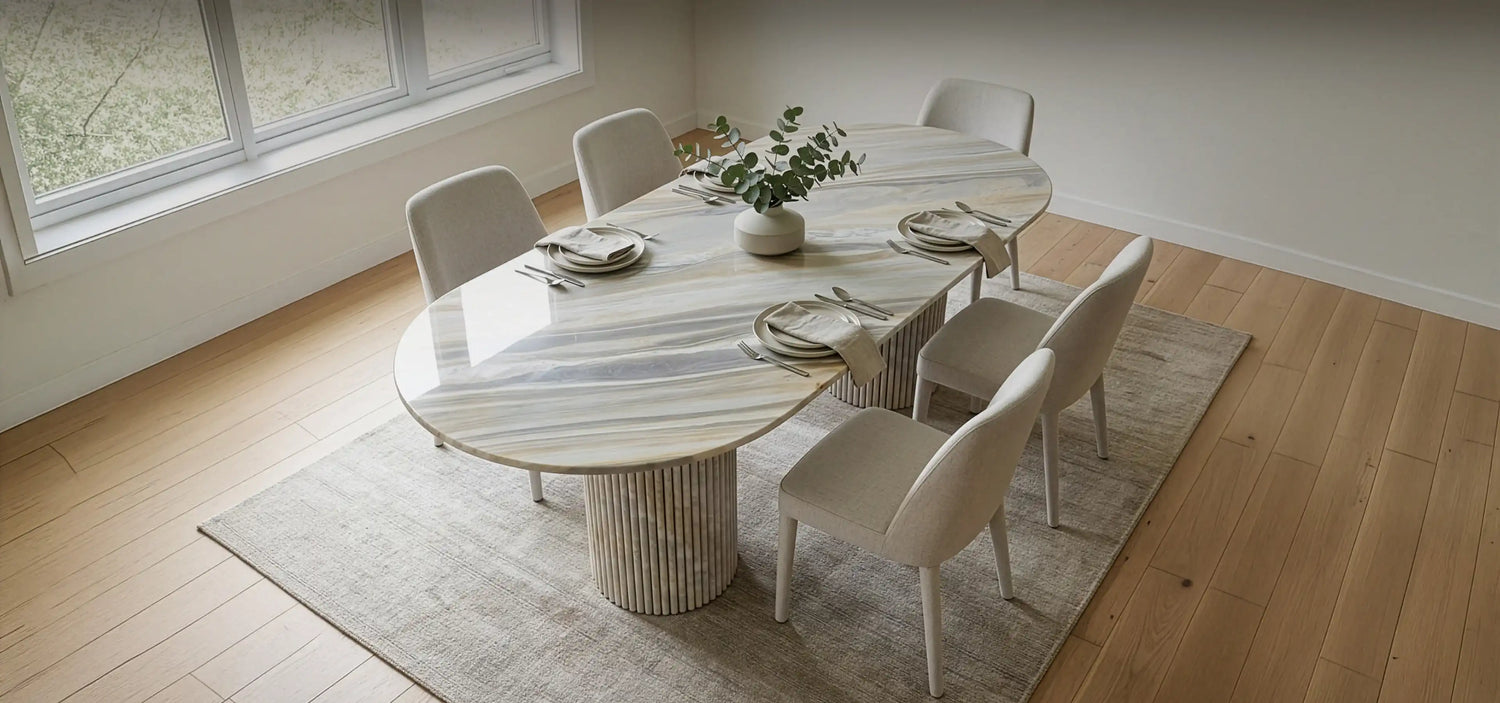 Dining room with a round marble table and chairs on a wooden floor.