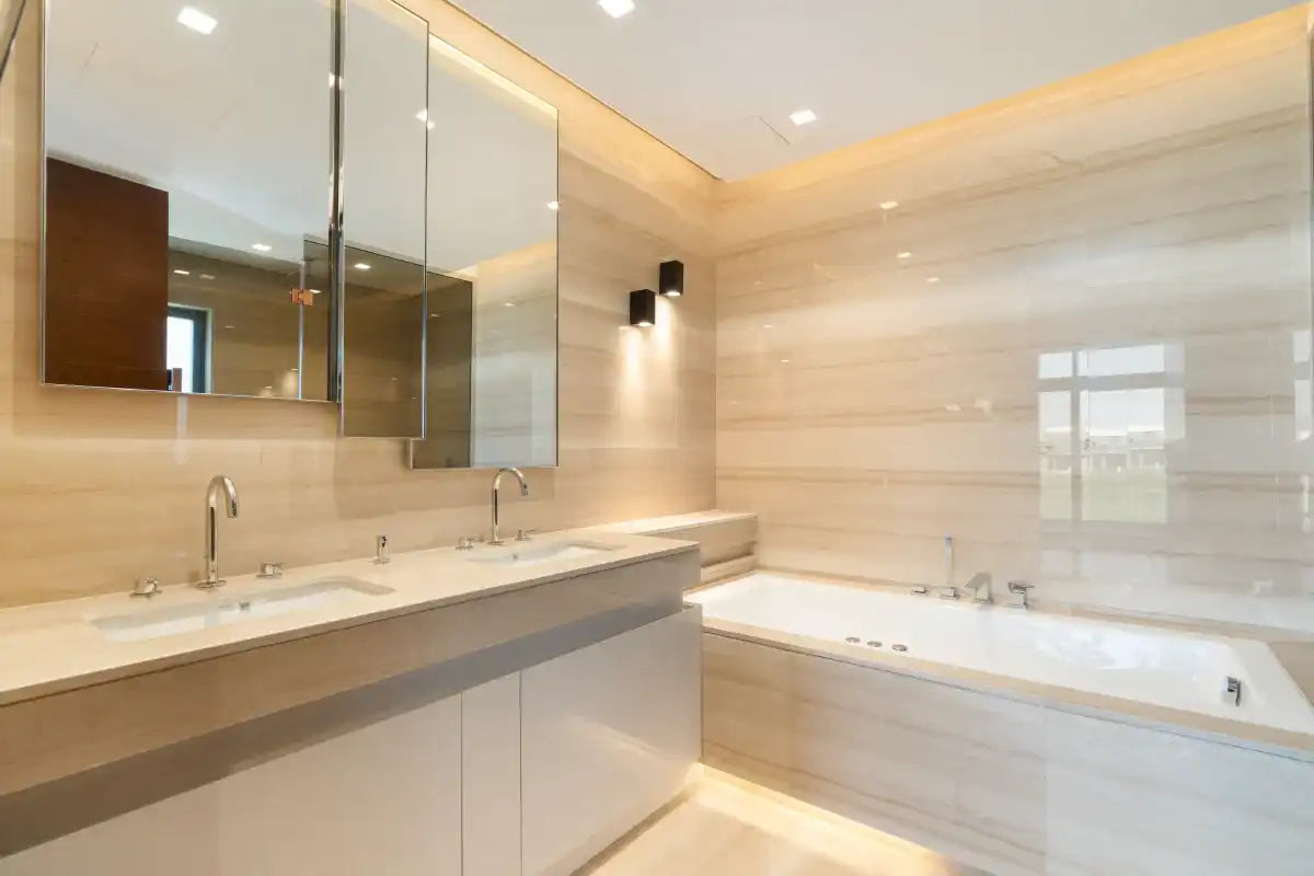 Modern bathroom with double sinks, large mirrors, and a built-in bathtub with beige tiles
