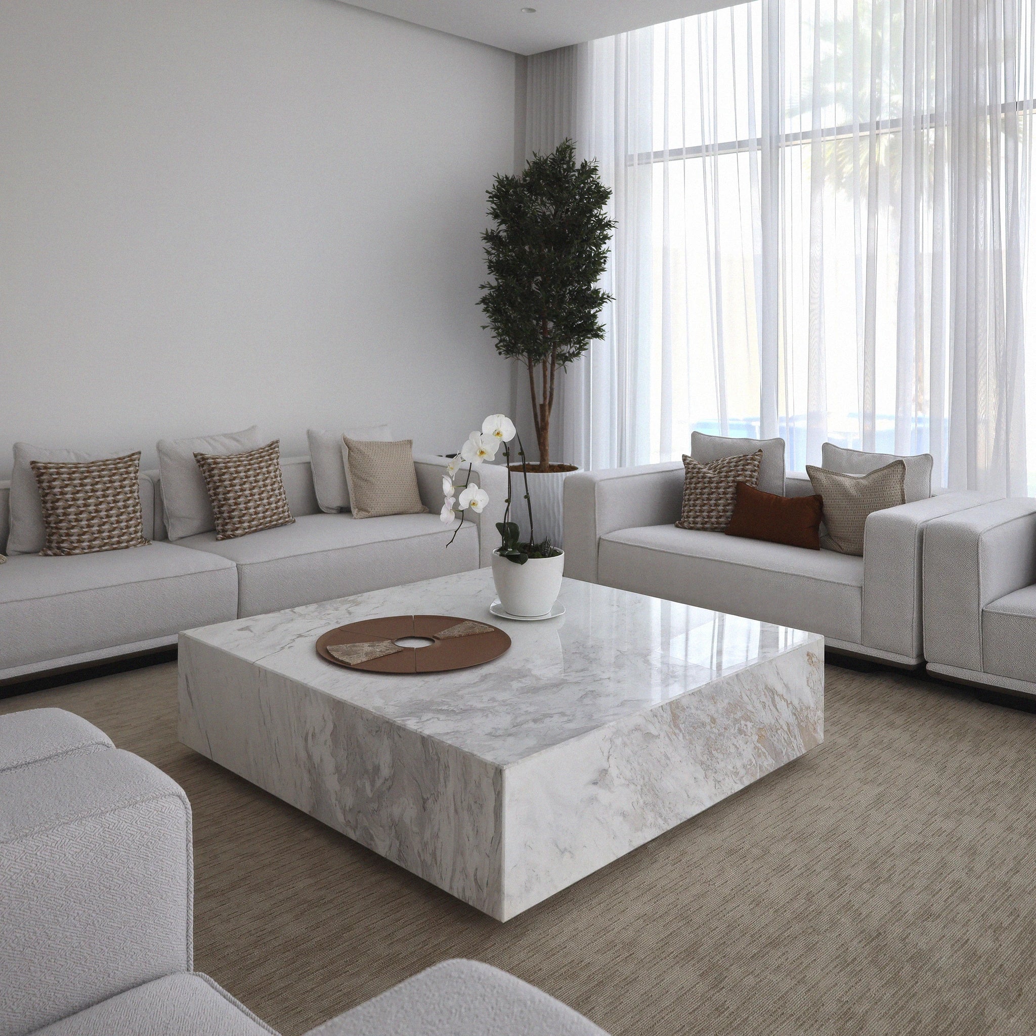 Bamo square marble coffe table from Marbeya Charm in the midldle of modern living room, surrounded with light grey sofas, a large window with normal lighting and transparent curtains, an artificial tree in the corner