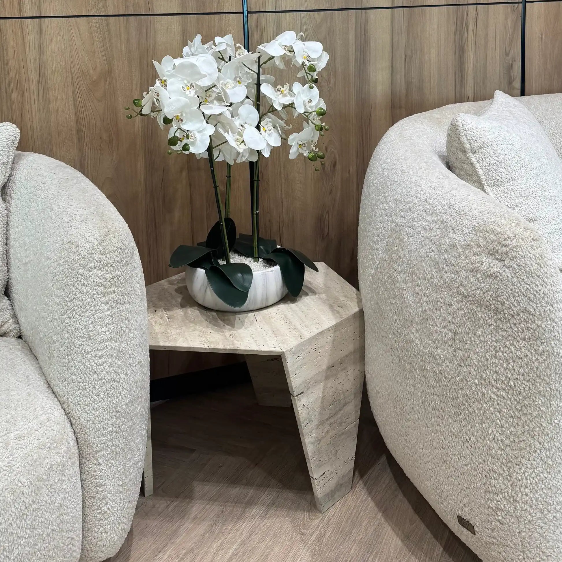 Narwin coffee table from Marbeya Charm between two armchair with vase of orchid flower on it