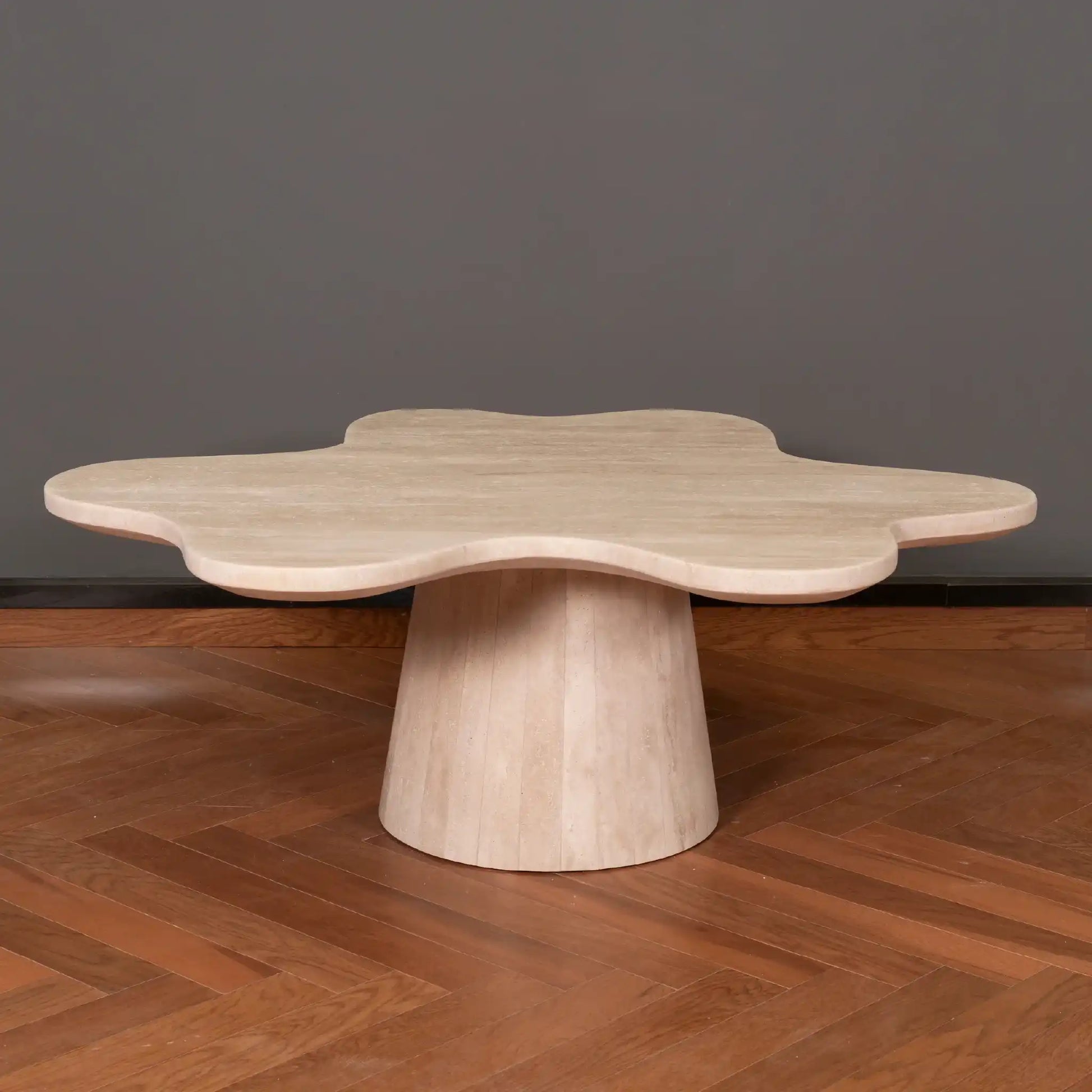 Petalo Travertine coffee table with a unique design on a wooden floor against a dark wall