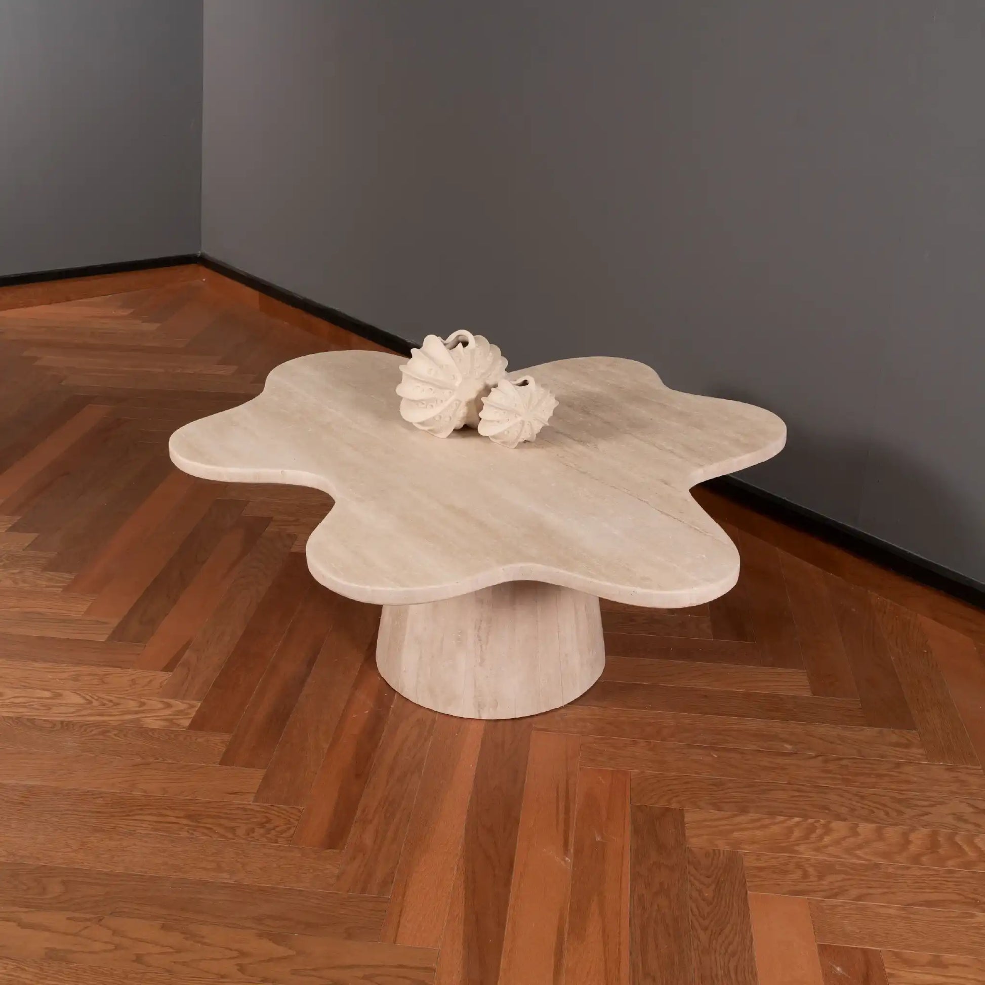 Petalo Travertine coffee table with a unique design on a wooden floor against a gray wall.