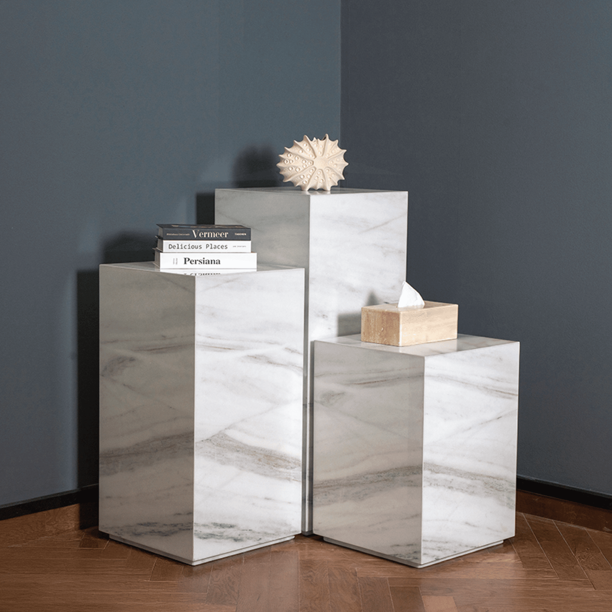 Set of marble side tables against a dark wall.