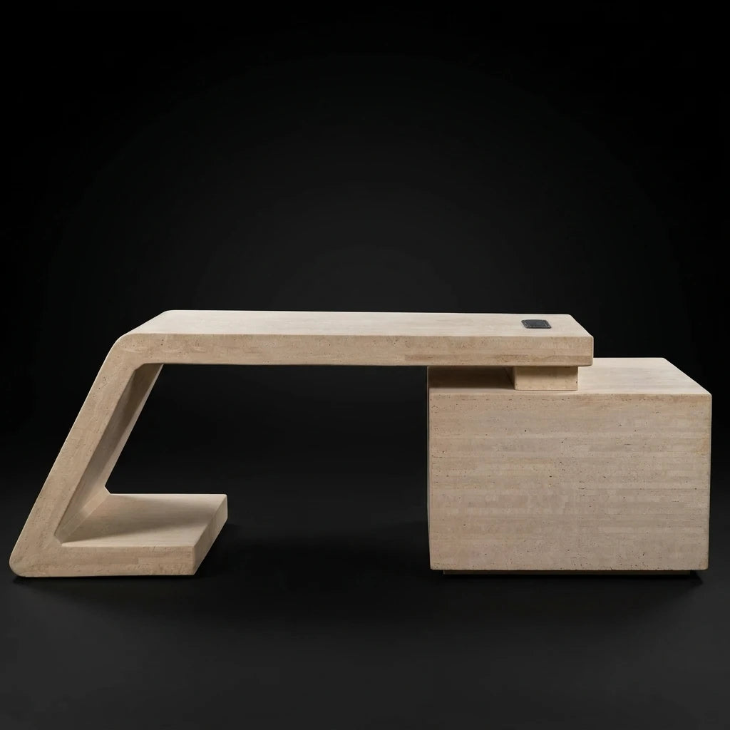 A modern minimalist stone office table with a light beige travertine finish, featuring a geometric triangular base and a rectangular storage drawers, set against a solid black background.