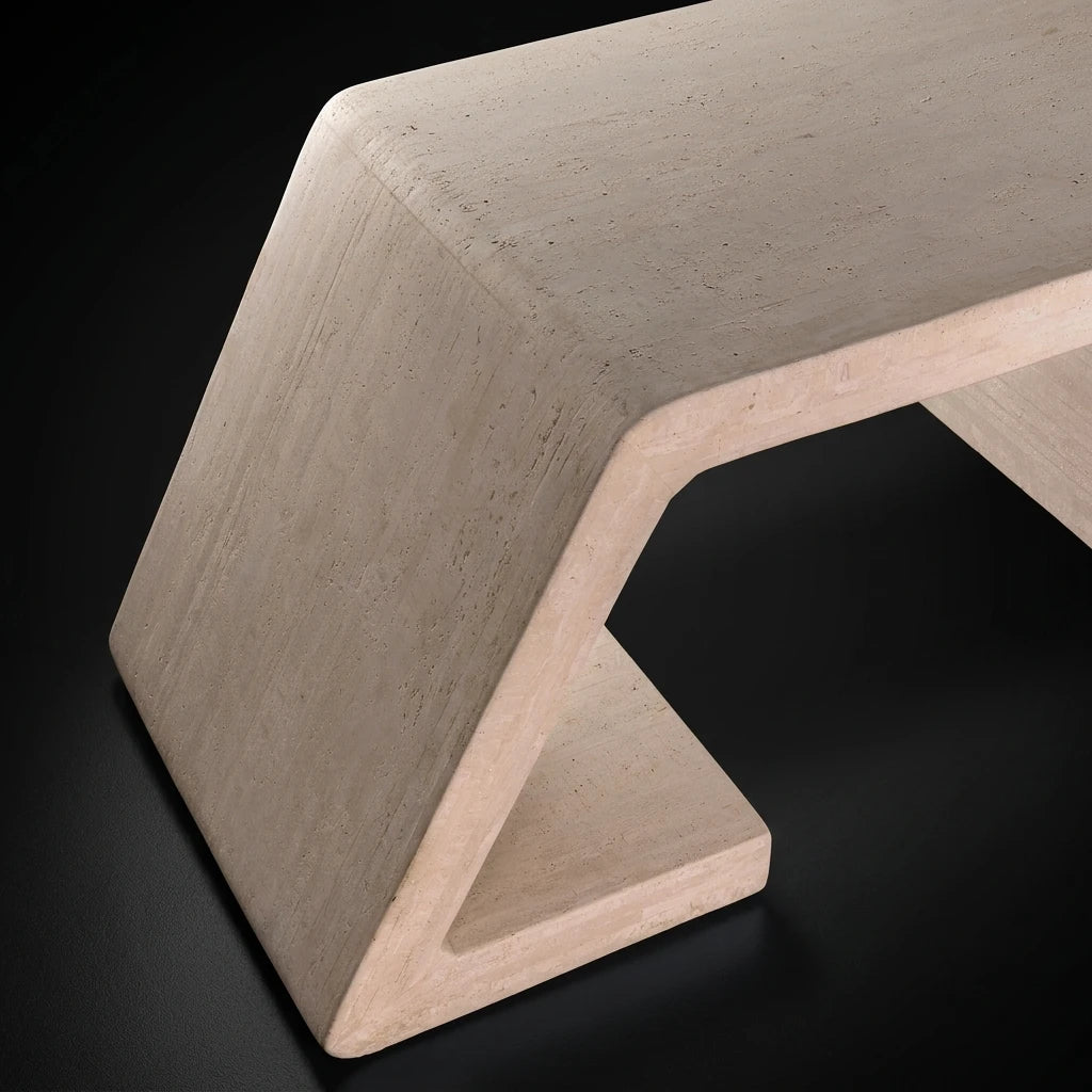 A close-up of a modern Z-shaped base of Strata office desk with a light beige travertine finish, set against a solid black background.